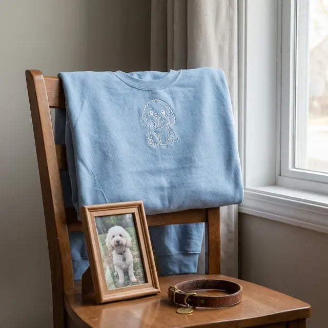 A sweatshirt on a chair beside a framed photo of a dog and a collar